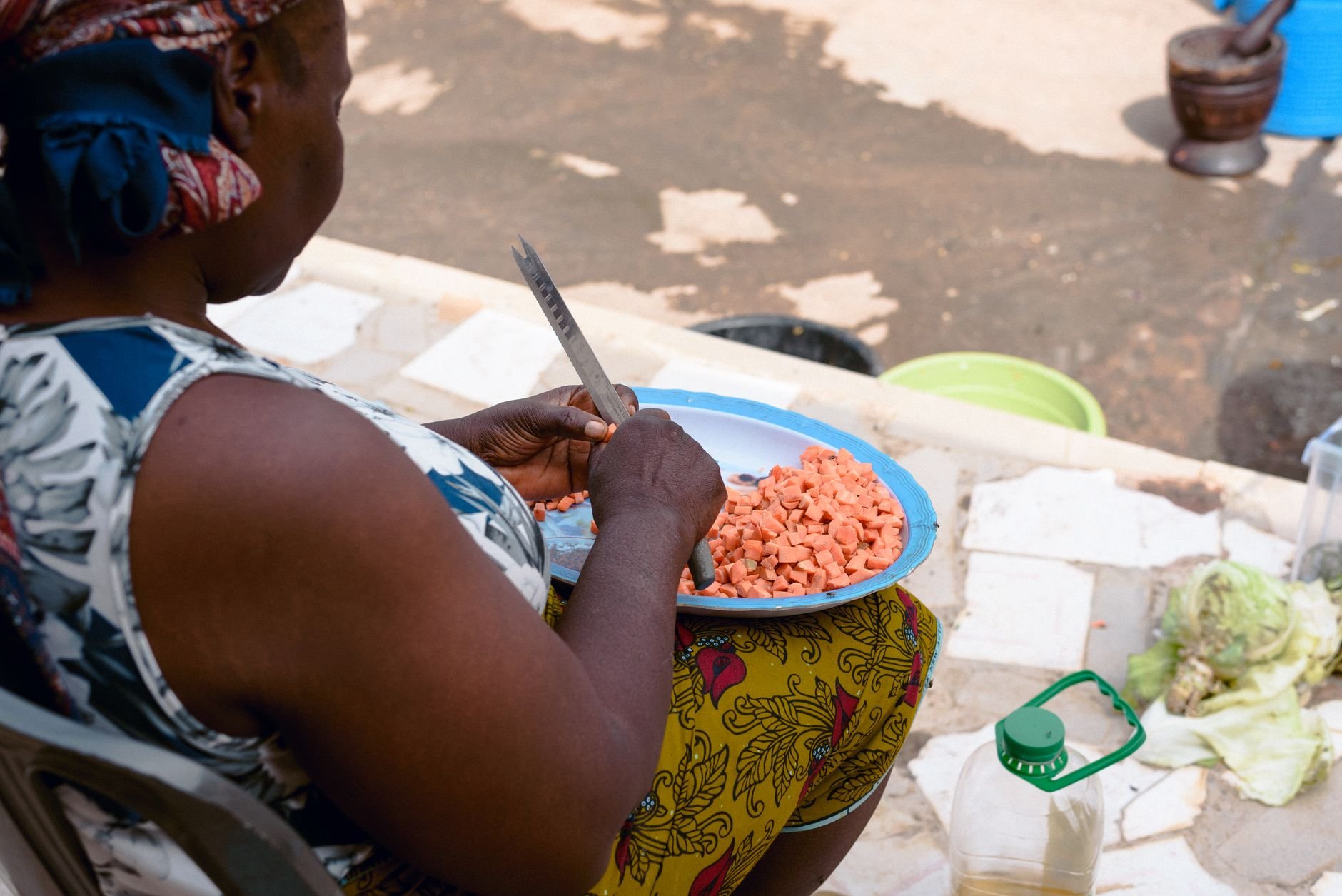 African woman chopping vegetables outdoors in Jos, Nigeria, showcasing home cooking culture.